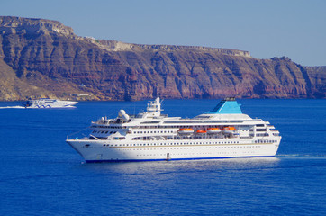 White classic Celestyal Cruises cruiseship or cruise ship liner anchored in bay of volcanic Greek...