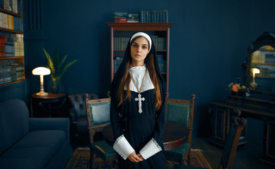Young nun in a cassock holds book