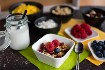 Schüssel mit leckeren Müsli. Dazu Kokosmilch im Einmachglas und Zutaten für das Müsli
