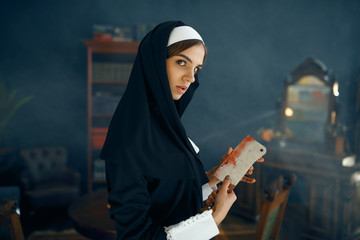 Crazy nun in a cassock holds bloody knife