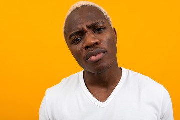 portrait of a serious handsome black blond african man close-up on an orange background