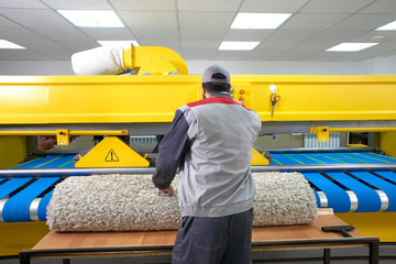 Laundry worker in the process of working on automatic machine for carpet washing in dry cleaning