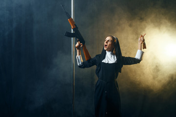 Young nun in a cassock holds assault rifle