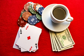 Playing cards with chips a cup of coffee on dollars on a red background