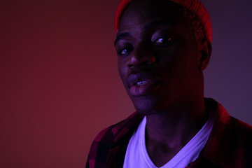 Closeup portrait of a stylish handsome black man looking at the camera in neon light in the shade