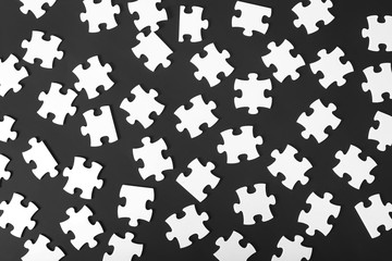 Scattered white puzzles on a dark background.