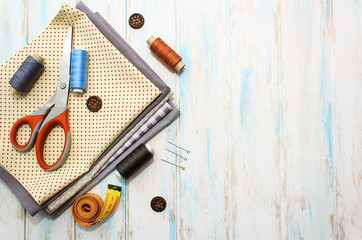 Sewing tools and fabric on a white background. Concept for needlework, stiching, embroidery and tioloring. Sewing multicolored threads, needles. Top view, flatlay whith copy space.