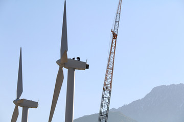 2 workers on top of wind turbine in a mountain desert area