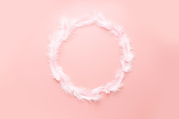 Easter pastel flat lay: pink fluffy feathers circle frame on a pink background