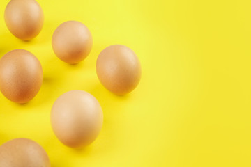 Raw brown chicken eggs on yellow background