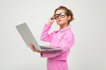 surprised attractive girl in a pink suit reads the news on a laptop on a white studio background