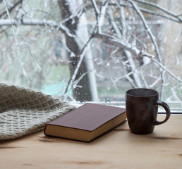 Snowy weather. Snow on trees and land. Bright white day. View outside the window sill with a cup of...