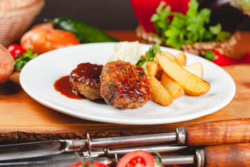 Juicy delicious meat cutlets with potato wedges on white plate. Russian cuisine.