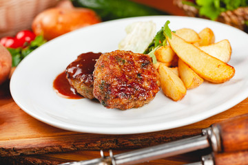 Juicy delicious meat cutlets with potato wedges on white plate. Russian cuisine.