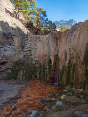 Cascada de Colores small allmost dry waterfall in a volcanic crater at Caldera de Taburiente, water stream is colorful colored by mineral water. La Palma, Canary Islands, Spain