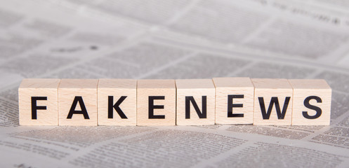 fakenews text on wooden cubes, newspaper as background