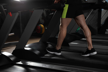 Fototapeta na wymiar Man working out on treadmill in modern gym, closeup of legs
