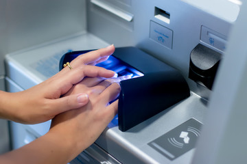 Close up of hand entering pin at an ATM. Finger about to press a pin code on a pad. Security code on an Automated Teller Machine. Female arms, ATM - entering pin