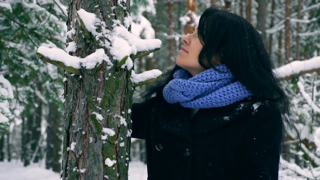 Beautiful Girl Comes Close To Pine Tree And Touches Trunk Covered With Snow. Walking in Winter Forest During Snowfall. Frost Weather In the Woodю 4K Slow motion 60 fps