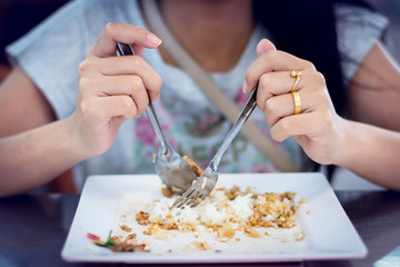 Woman holding a spoon, eating rice and fingers in two rings
