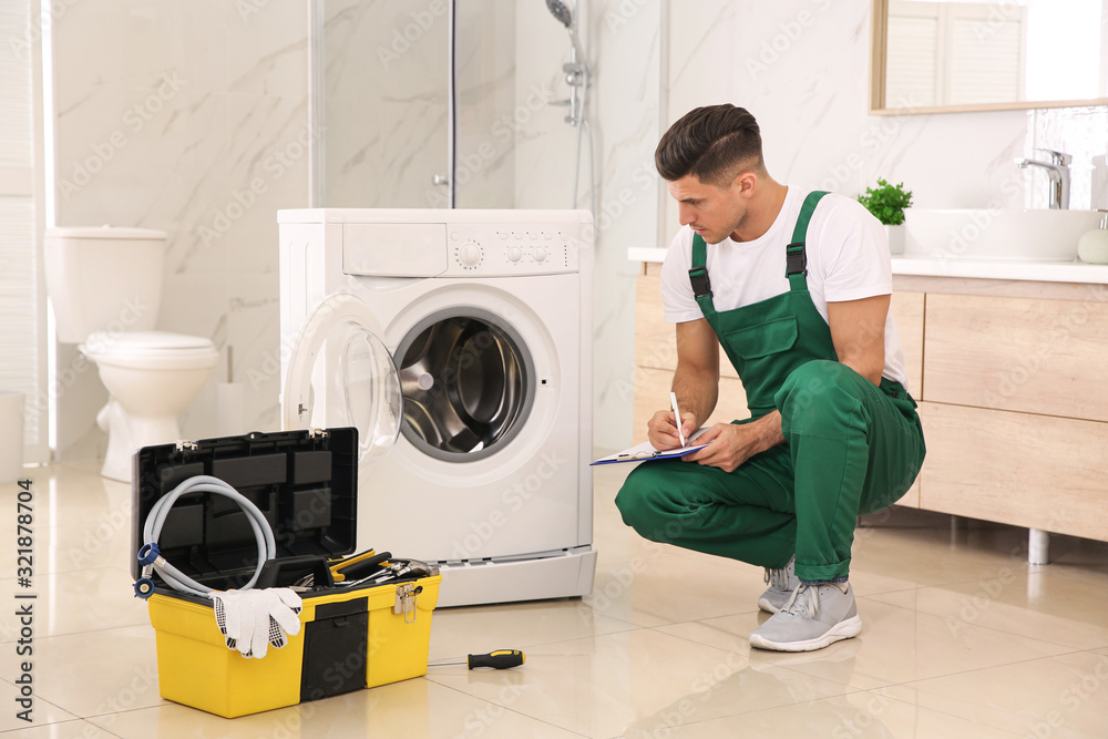 Wall mural Professional plumber repairing washing machine in bathroom