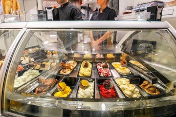 Refrigerated display case with a large assortment of soft ice cream in an Italian store