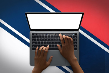 Mockup image of a person using a keyboard with a blank white laptop screen 