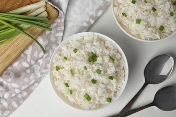 Bowls with tasty cooked rice on white table, flat lay