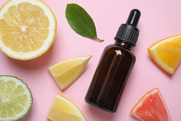 Flat lay composition with bottle of citrus essential oil on pink background