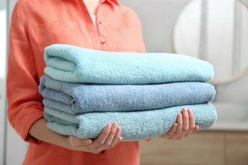 Woman holding fresh towels in bathroom, closeup