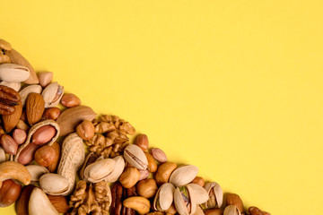 Different delicious nuts on yellow background, flat lay. Space for text
