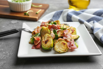Delicious roasted Brussels sprouts with bacon served on grey table