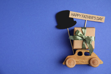 Flat lay composition with wooden car and gift box on blue background, space for text. Happy...