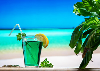 Close up of a glass of mint drink on a Caribbean beach with blue sea and blue sky. Sense of relaxation and tranquility. Tropical Caribbean vacation.