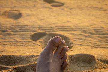 View of human foot over beach sand.