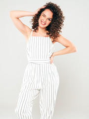 Obraz premium Portrait of beautiful smiling model with afro curls hairstyle dressed in summer hipster clothes.Sexy carefree girl posing in studio on gray background.Trendy funny and positive woman