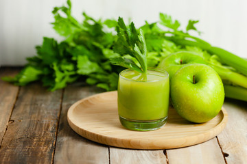 Healthy eating, food and vegetarian diet concept - glass of fresh green apple and celery juice or smoothie. Antioxidant detox beverage. Clean organic ingerdients. Close up, wooden background.
