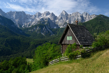 Fototapeta na wymiar Alpine hut in front of the impressive Julian Alps in Kranjska Gora, Slovenia