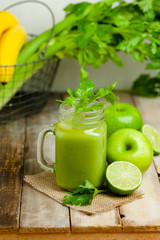 Healthy eating, food and vegetarian diet concept - mason jar of fresh juice or smoothie with apple, celery. Antioxidant detox beverage. Clean organic ingerdients. Close up, wooden background