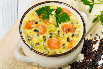 Cream of Chicken and Wild Rice Soup on White Wooden Background. Homemade Fresh Creamy Soup with Chicken, Carrot, Vegetables and Wild Rice. Selective focus.
