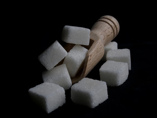 sugar cubes and wood spoon over black surface