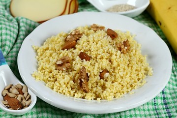 Millet porridge with walnuts and almonds.   Delicious salty breakfast on the white plate