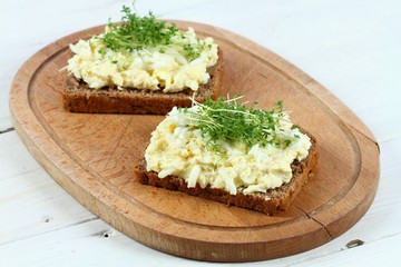 Egg salad over brown bread with garden cress. Homemade spread made from eggs, mayonnaise and mustard on white table