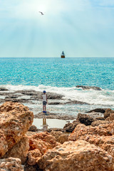A boy stands on the shore and looks at the ship