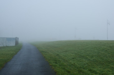 Fototapeta na wymiar Path through a grassy park on a very foggy day, taken in Salthill near Galway