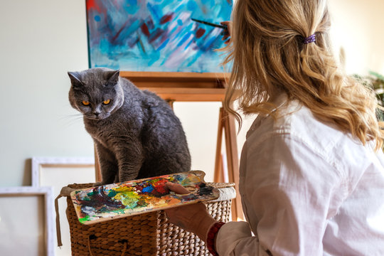 Woman and her pet in art studio. Artist enjoying painting with her british shorthair cat