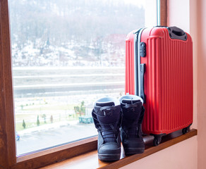 Snowboard boots and a red suitcase. Concept of travel leisure and sports. Copy space