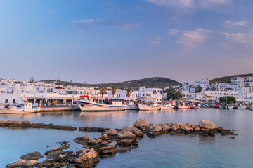 Naklejka na ściany i meble Panoramic view of sunset at popular tourist attraction in Paros island, Naousa town. Promenade zone with bars and restaurants along harbor. Aegean Sea and boats in quay. Amazing evening in Greece