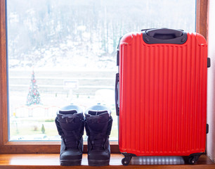Snowboard boots and a red suitcase. Concept of travel leisure and sports. Copy space