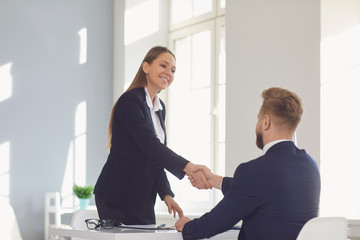 Successful office interview. The conclusion of the contract. Businessman and businesswoman handshake at the table after meeting.